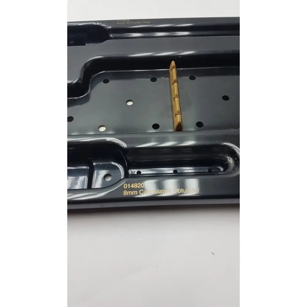 A gold-colored 8mm cannulated obturator from smith & nephew endoscopy portal accessory system in a black plastic tray