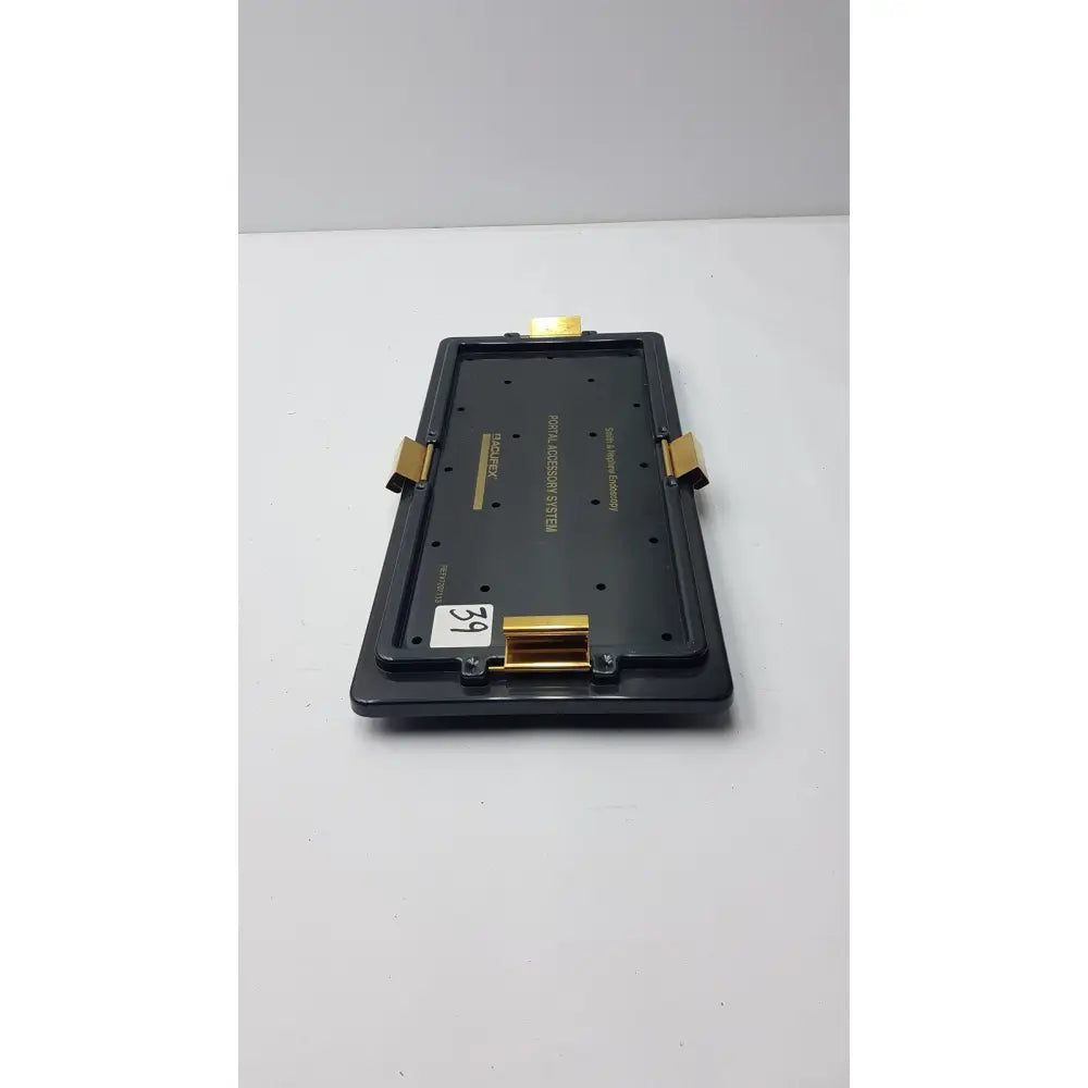 Black plastic smith & nephew endoscopy portal accessory tray with gold metal clips and white price tag