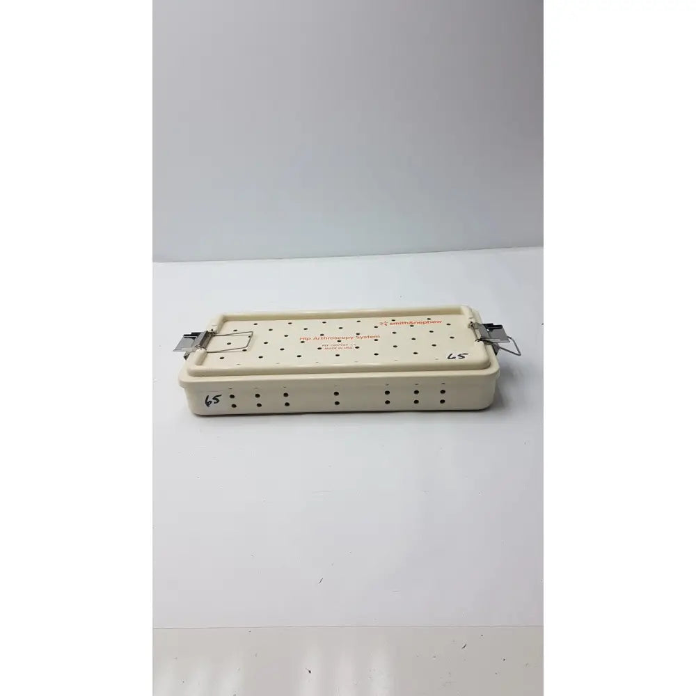 Cream-colored plastic smith & nephew ref 7207934 hip arthroscopy empty tray with metal clamps and grid holes