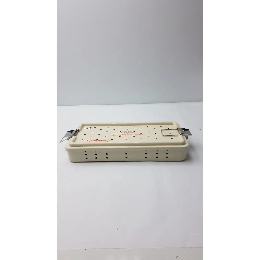 Cream-colored plastic Smith & Nephew ref 7207934 hip arthroscopy empty tray with metal latches and perforations