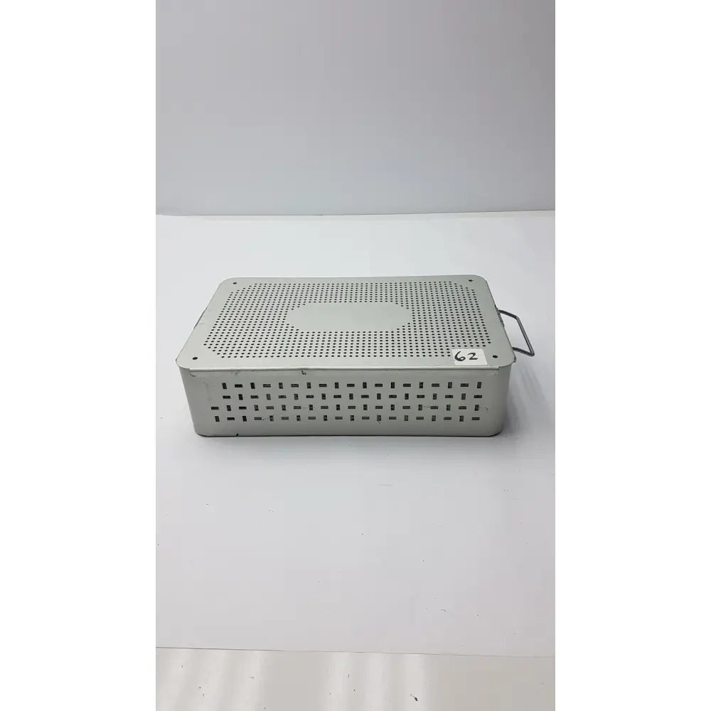 Solid brass sterilization storage container with lid featuring a silver metallic perforated surgical instrument tray and handle