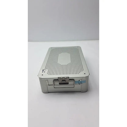 Solid brass sterilization storage container with silver metallic perforated lid and numbered label for sterilization use