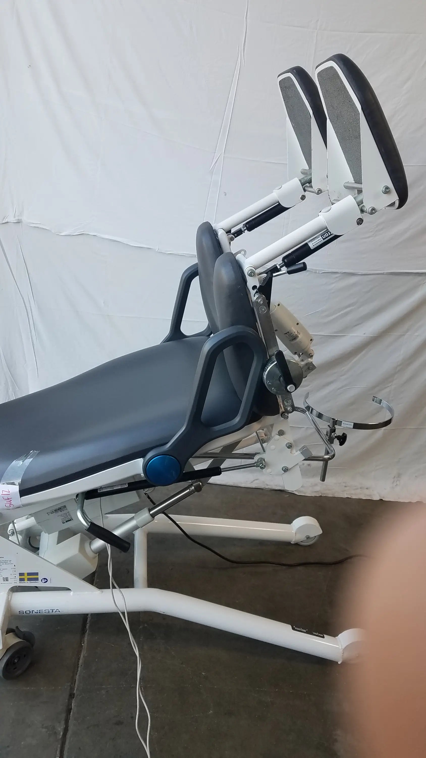 Adjustable sonesta s3 ultimate patient positioning procedure chair with black padded surface and white metal frame
