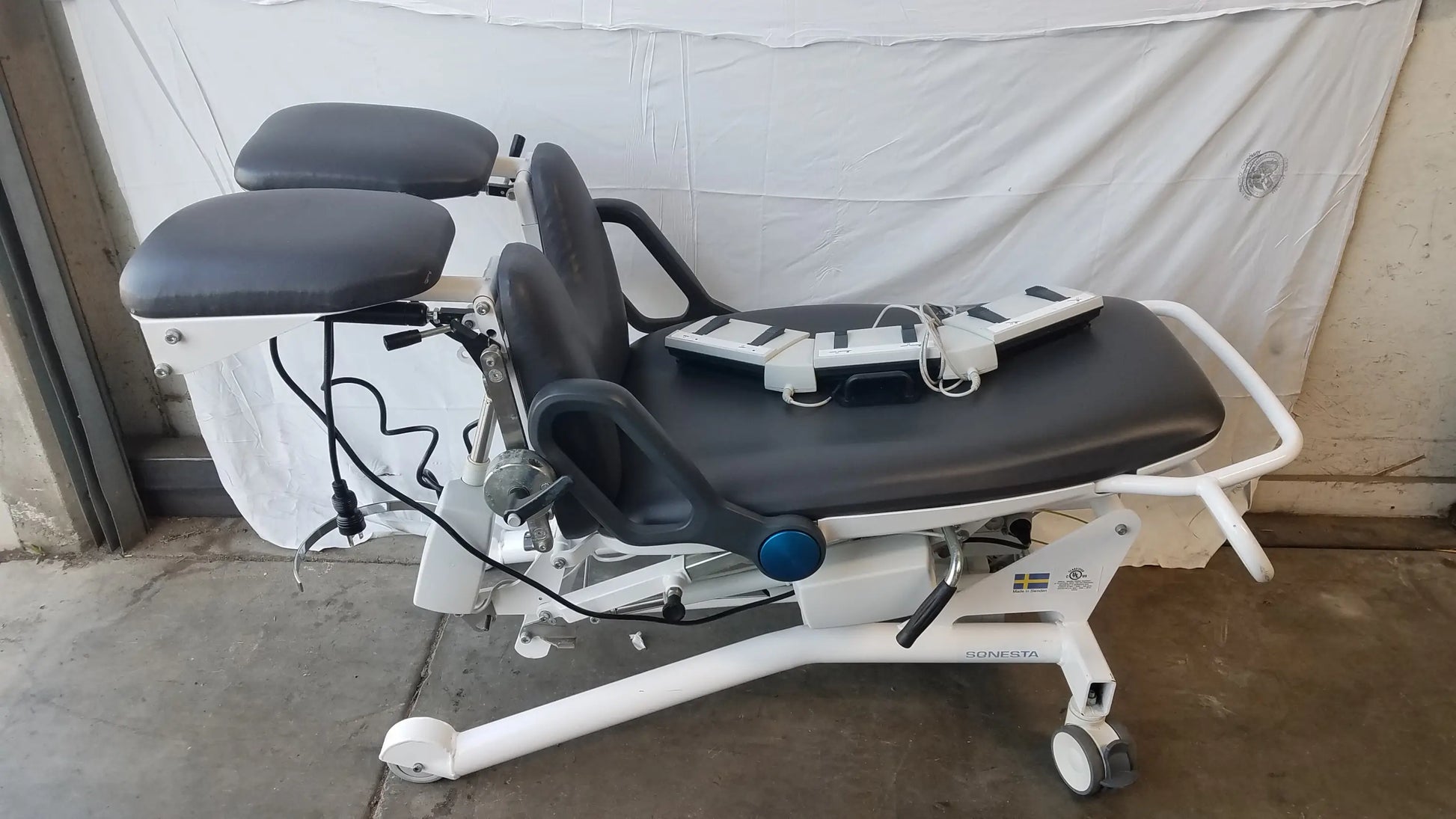 White sonesta s3 ultimate patient positioning procedure chair with black padded surfaces and adjustable components