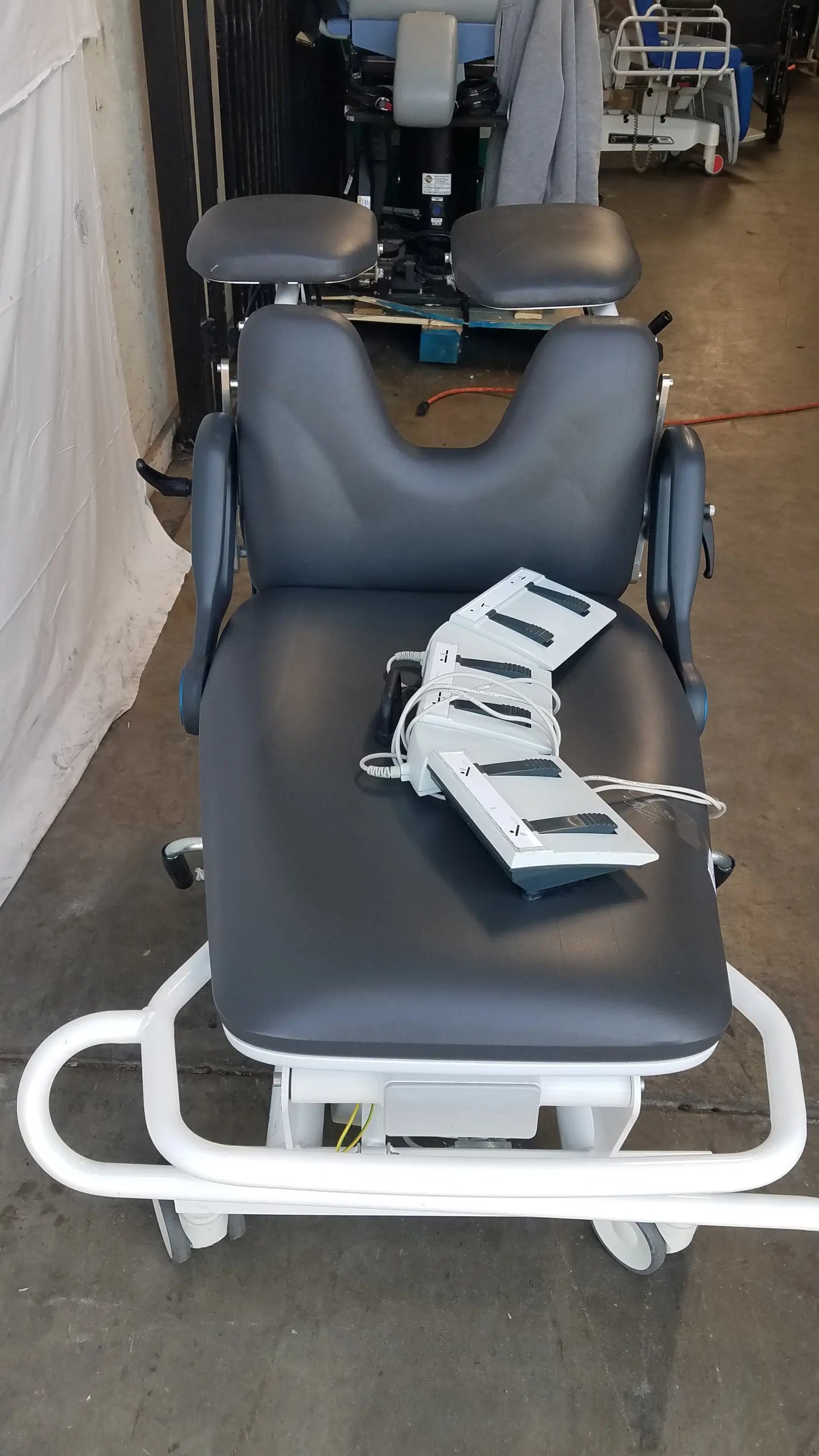 Black padded sonesta s3 ultimate patient positioning procedure chair with white metal frame and adjustable headrest