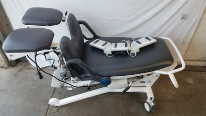 White Sonesta S3 ultimate patient positioning procedure chair with black padded surfaces and adjustable footrests