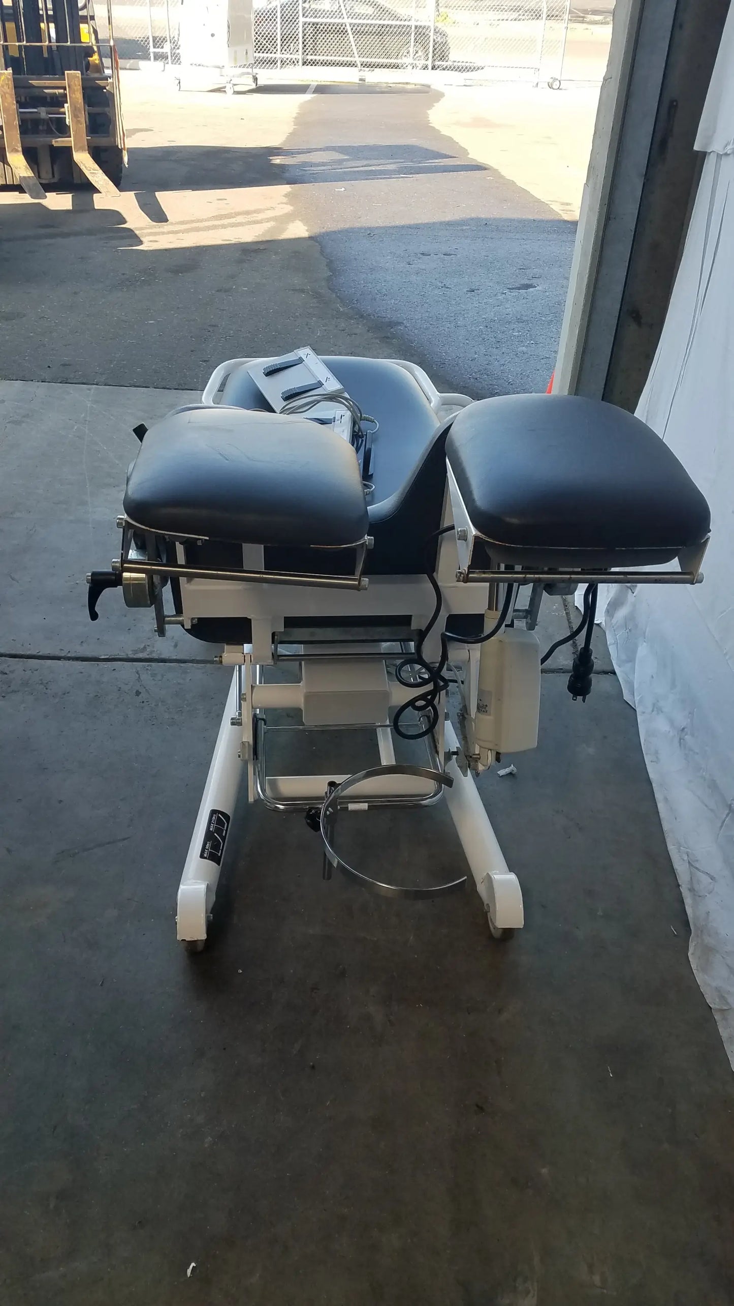 Black leather-covered adjustable Sonesta S3 ultimate patient positioning procedure chair with white metal frame and wheels