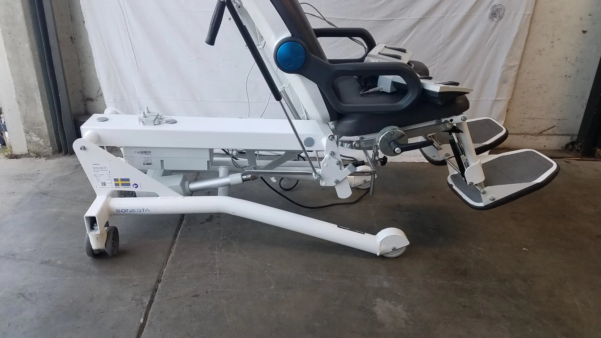 White motorized recliner Sonesta S3 ultimate patient positioning procedure chair with black seat, footrests, and blue control knob