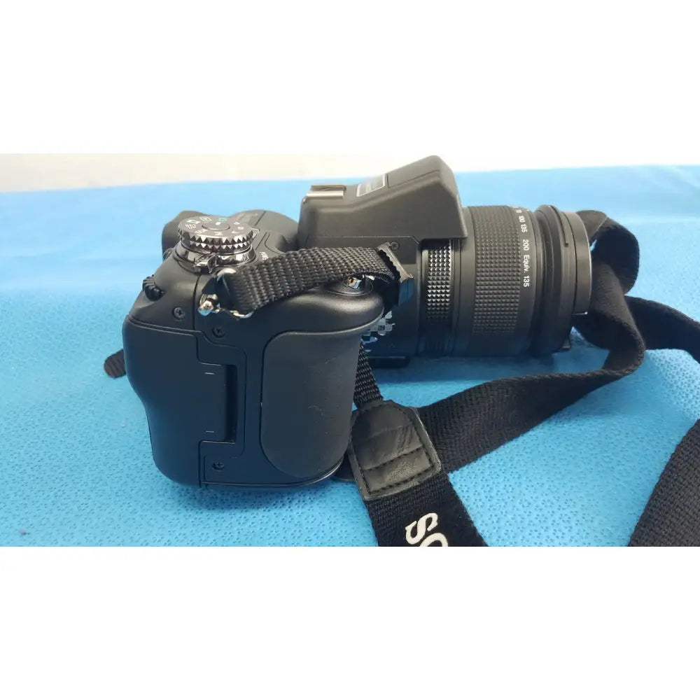 Black sony cyber-shot dsc-f828 digital still camera with mounted lens and attached strap with ac power adapter