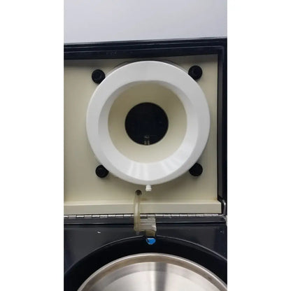 White circular component with black aperture and screws on beige panel in sorvall cell washer centrifuge cell washing system