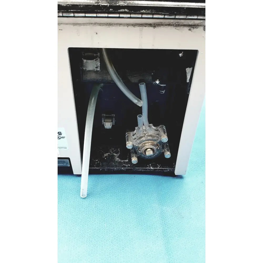 Clear plastic tubing assembly with metallic fittings inside white sorvall cell washer for centrifuge cell washing system