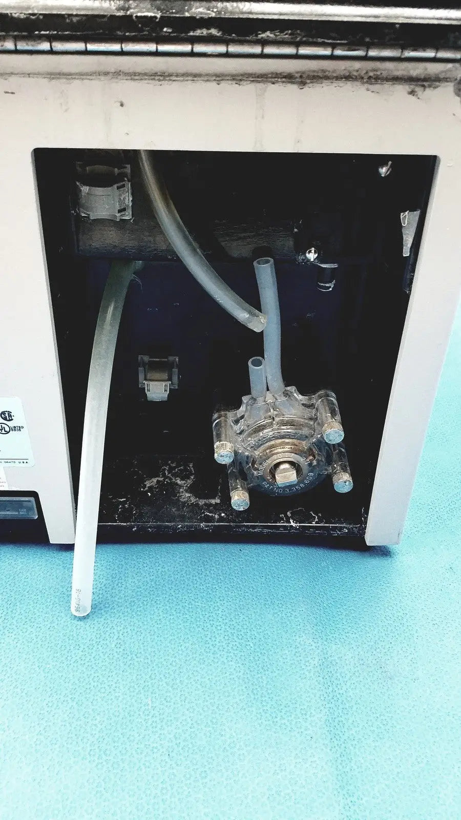 Clear plastic tubing assembly with metallic fittings inside white sorvall cell washer for centrifuge cell washing system