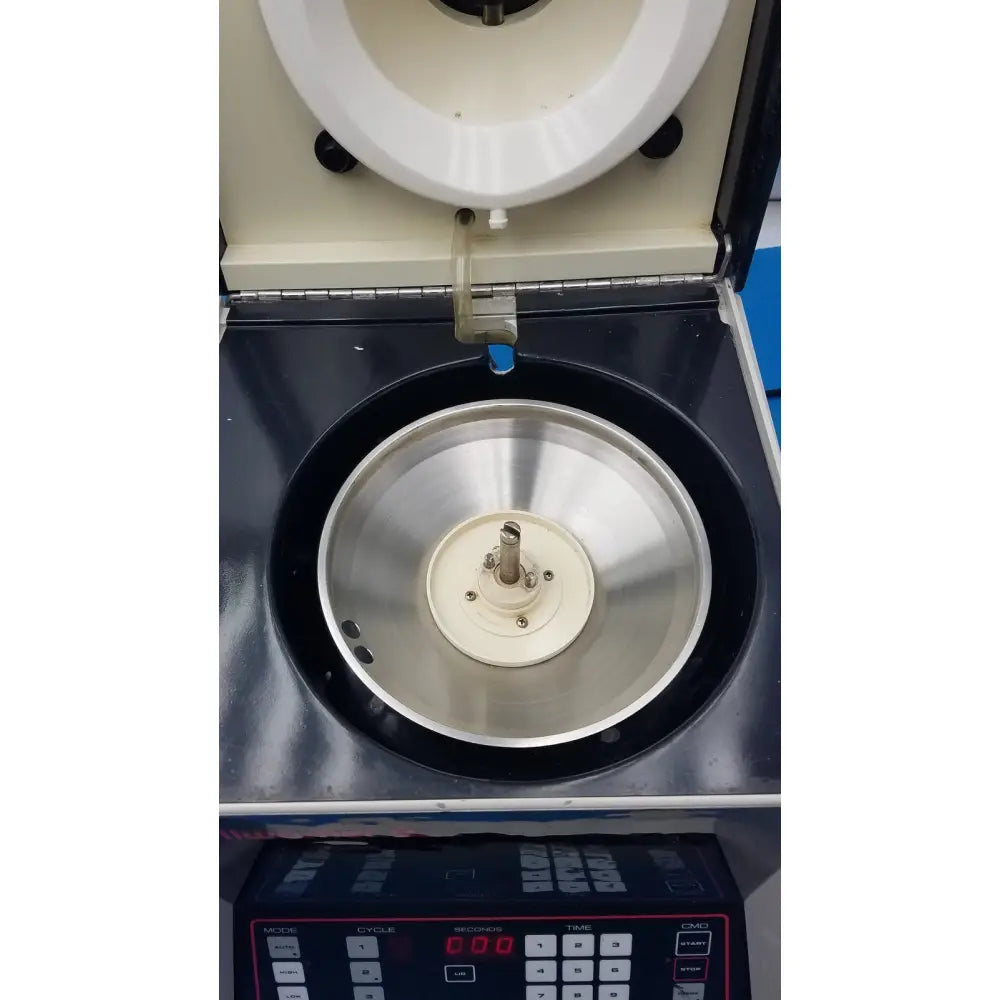 A stainless steel centrifuge rotor with white hub inside an open sorvall cell washer for centrifuge cell washing