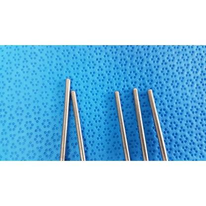 Five slender metallic sewing needles on textured blue surface next to sterile specimen containers with orange cap and tamper-evident label