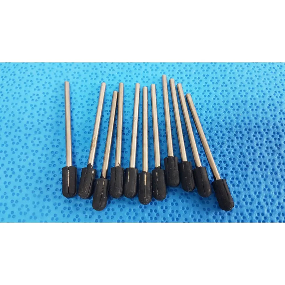 Ten metallic drill bits with black rubberized tips arranged on blue surface beside specimen containers with tamper-evident label and orange cap