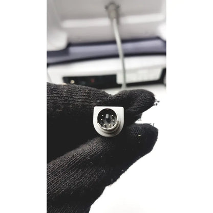 Silver-colored square computer connector with circular pins on back side of sperian titmus i300 vision screening system