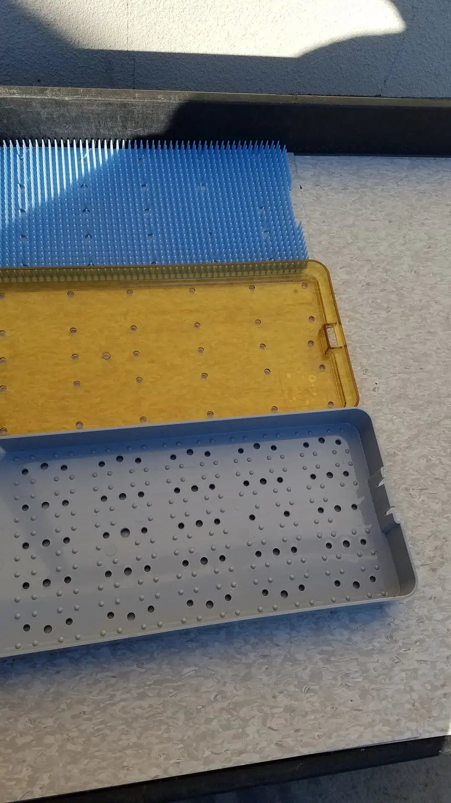 Blue yellow and gray plastic perforated surgical instrument trays designed as sterilization basket trays for stainless steel use