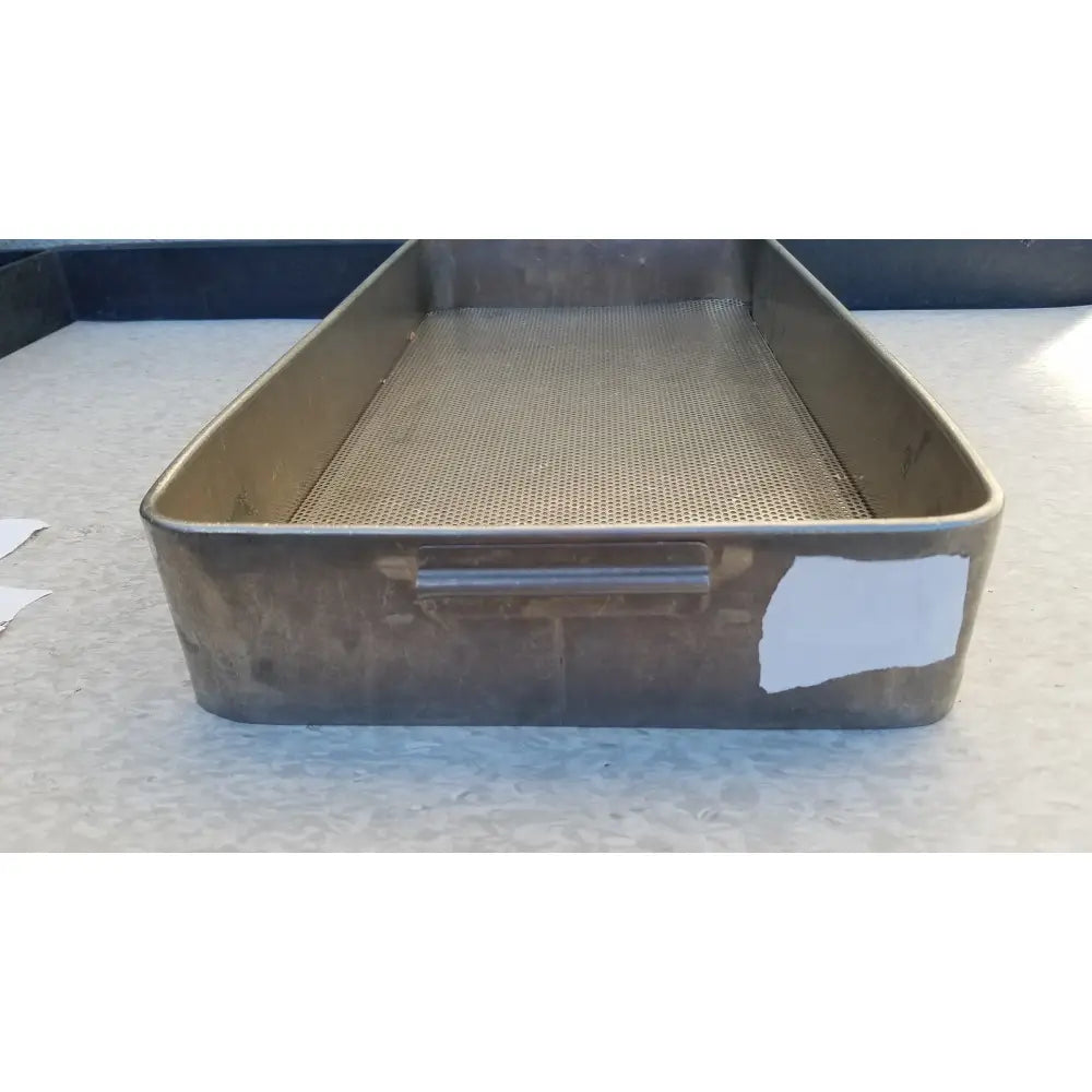 A rectangular stainless steel sterilization basket tray with perforated mesh and sturdy handle showing signs of wear