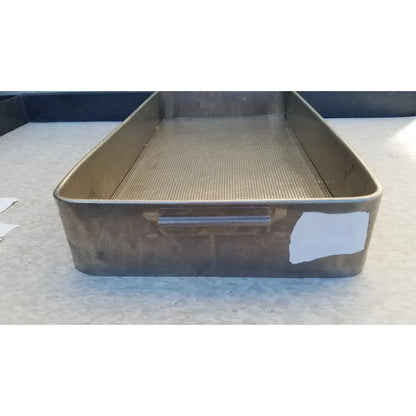 A rectangular stainless steel sterilization basket tray with perforated mesh and sturdy handle showing signs of wear