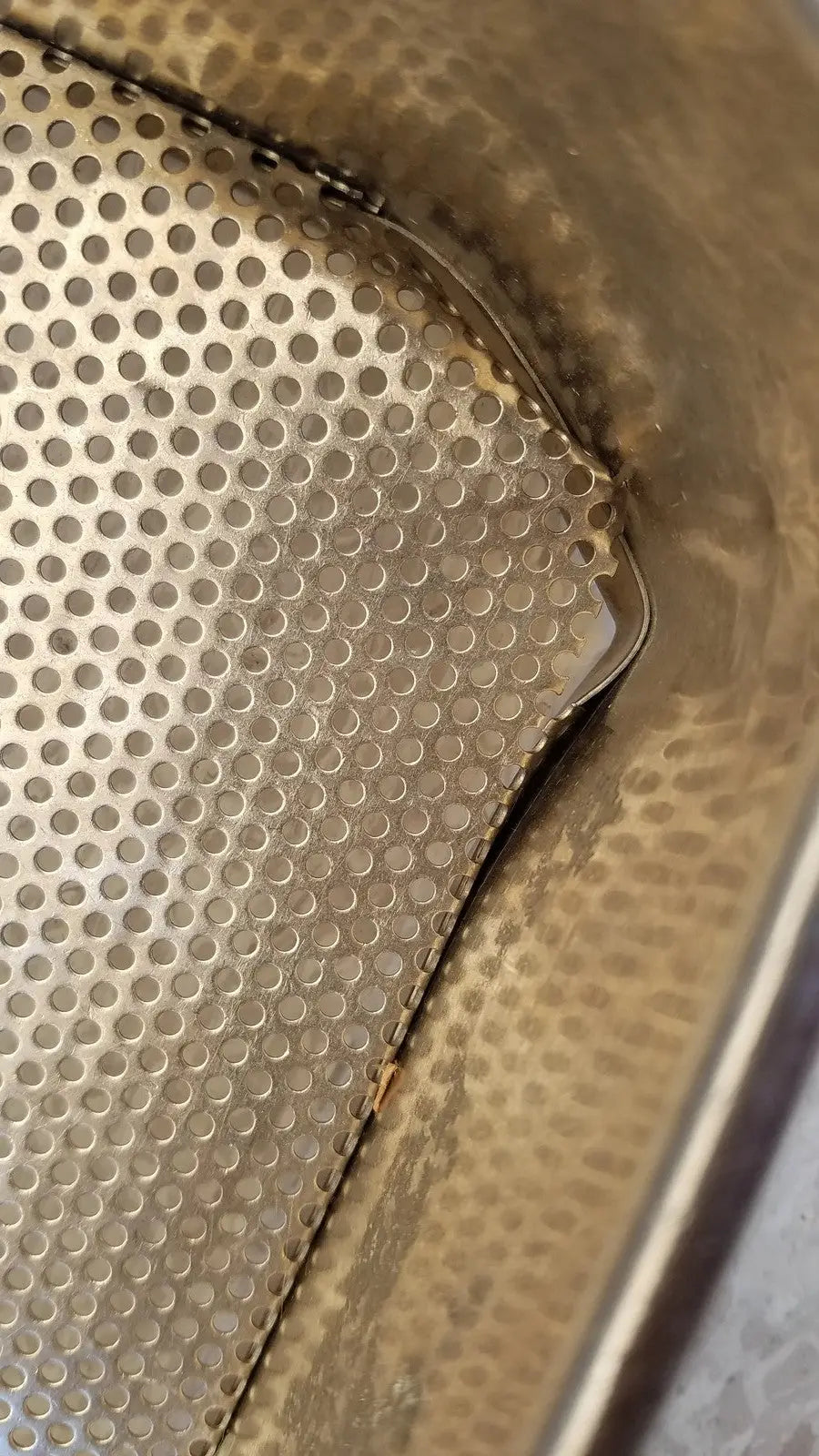 A metallic stainless steel sterilization basket tray with perforated textured surface and rounded edges