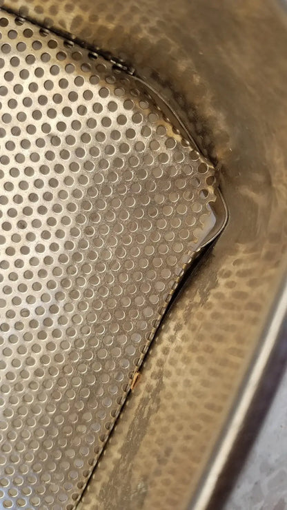 A metallic stainless steel sterilization basket tray with perforated textured surface and rounded edges