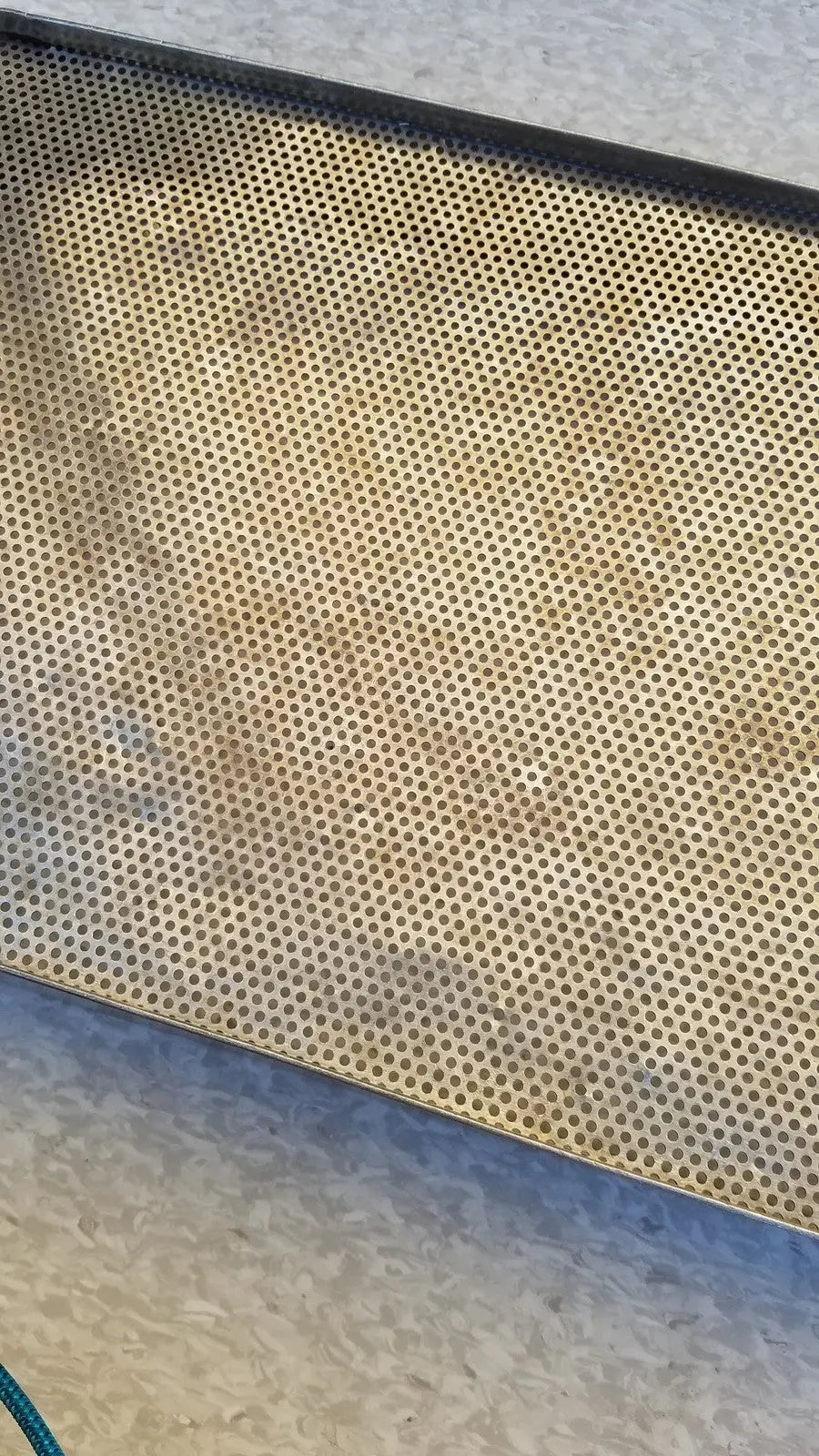 Stainless steel sterilization basket tray in rectangular perforated design with golden brown patina and circular holes