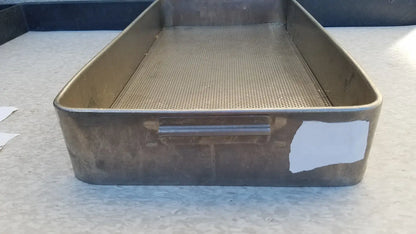 A rectangular stainless steel sterilization basket tray with perforated mesh and sturdy handle showing signs of wear