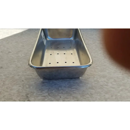 A rectangular stainless steel vollrath sheboygan tray case with perforated bottom and raised edges for draining