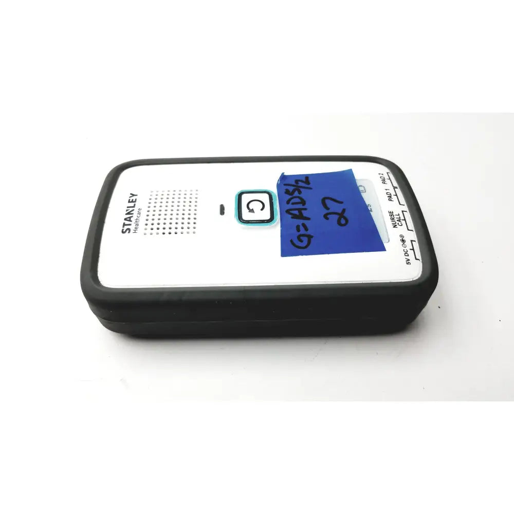 Black and white stanley healthcare m200 healthcare nurse call device with blue sticky note on top surface