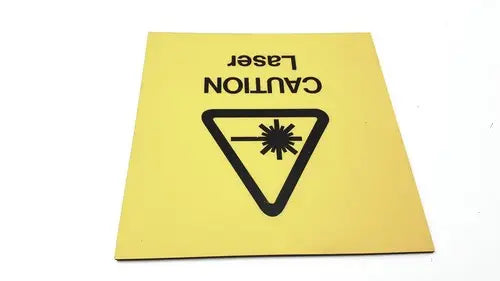 Yellow square fun wall sign with black caution laser text and laser zone hazard symbol indicating wall sign ahead
