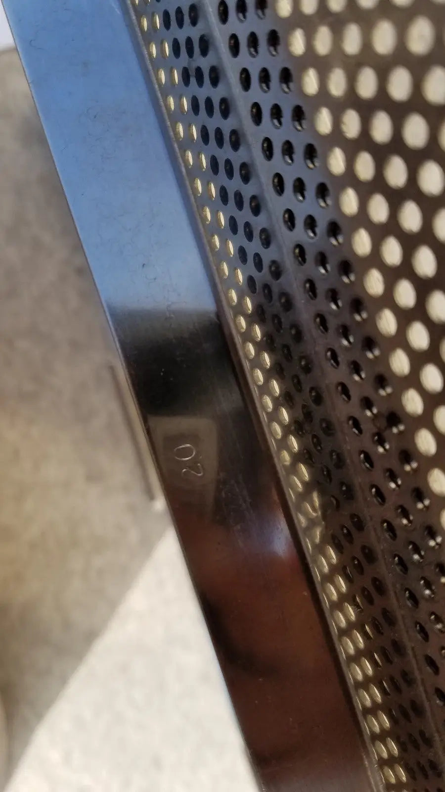 Shiny metallic edge with perforated pattern and engraved 02 marking on sterilization case tray for surgical instruments