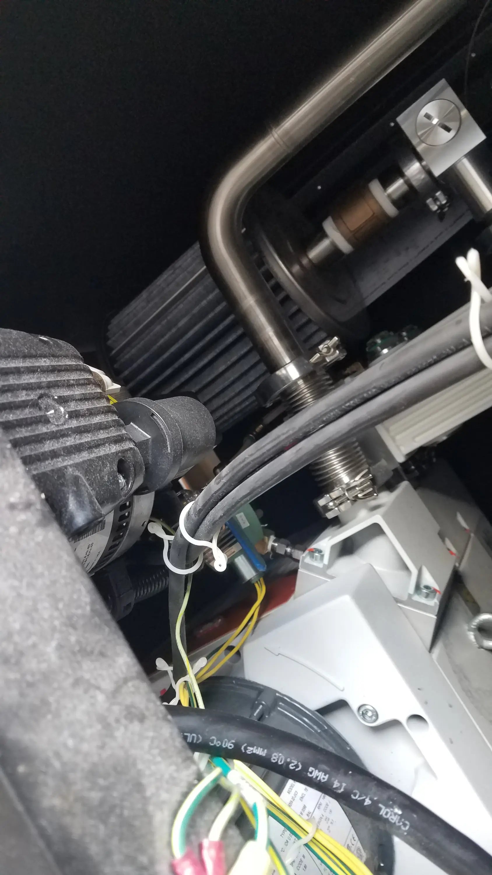 Black ribbed engine component with metallic piping and bundled wires on the back of steris v-pro max low temperature sterilization system