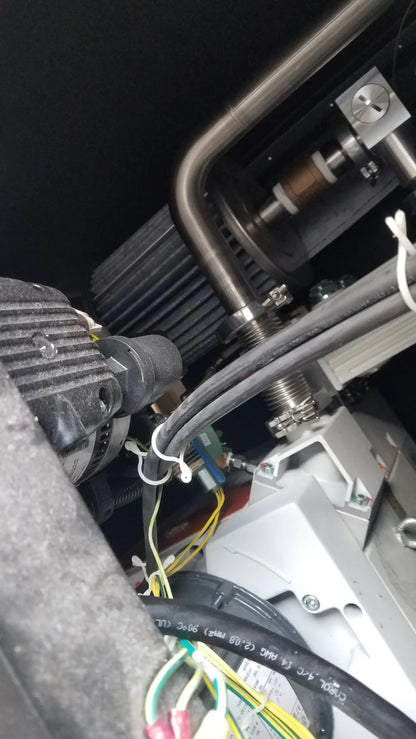 Black ribbed engine component with metallic piping and bundled wires on the back of steris v-pro max low temperature sterilization system