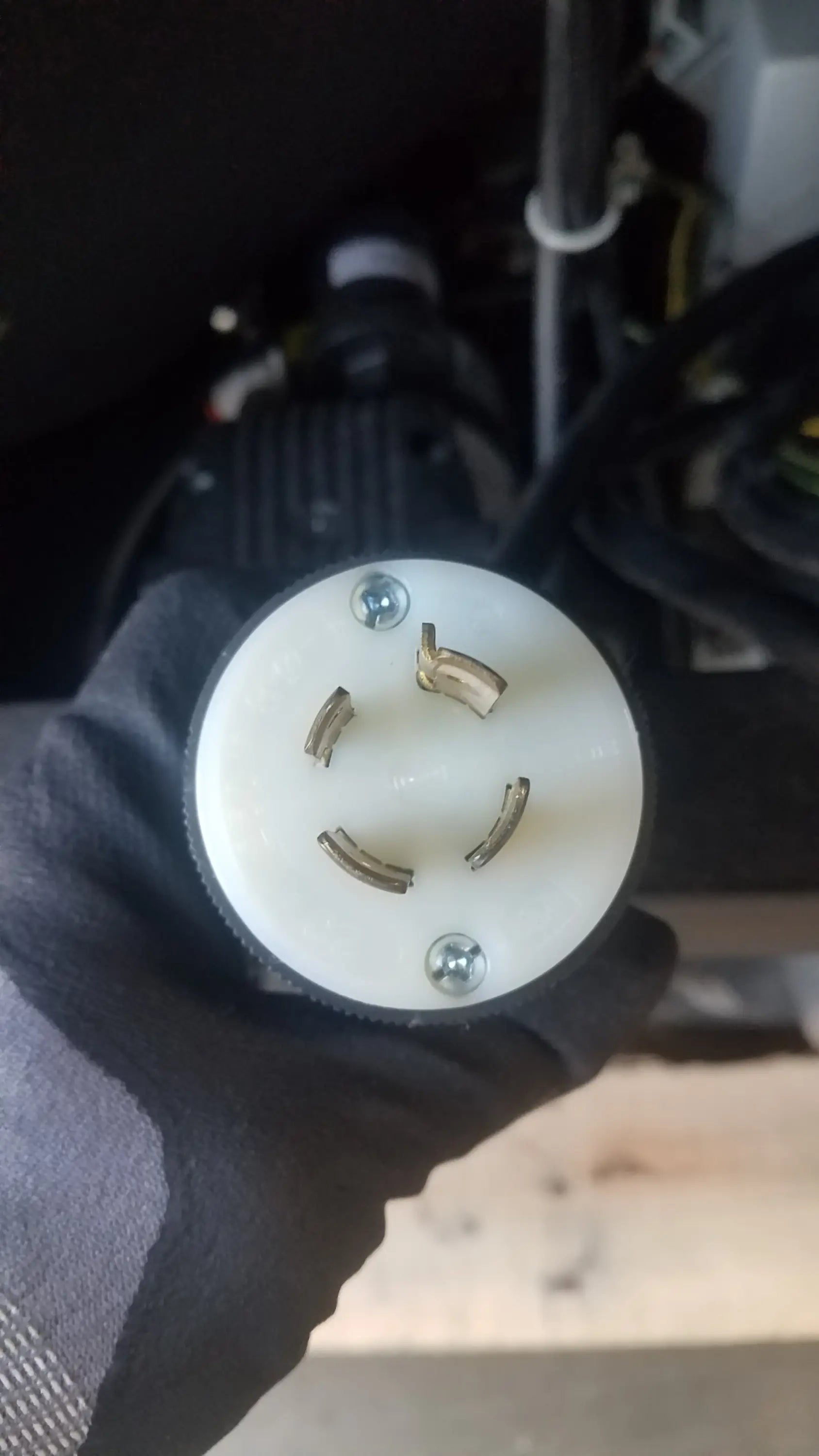White circular electrical plug with three metallic prongs held in black glove for steris v-pro max low temperature sterilization system