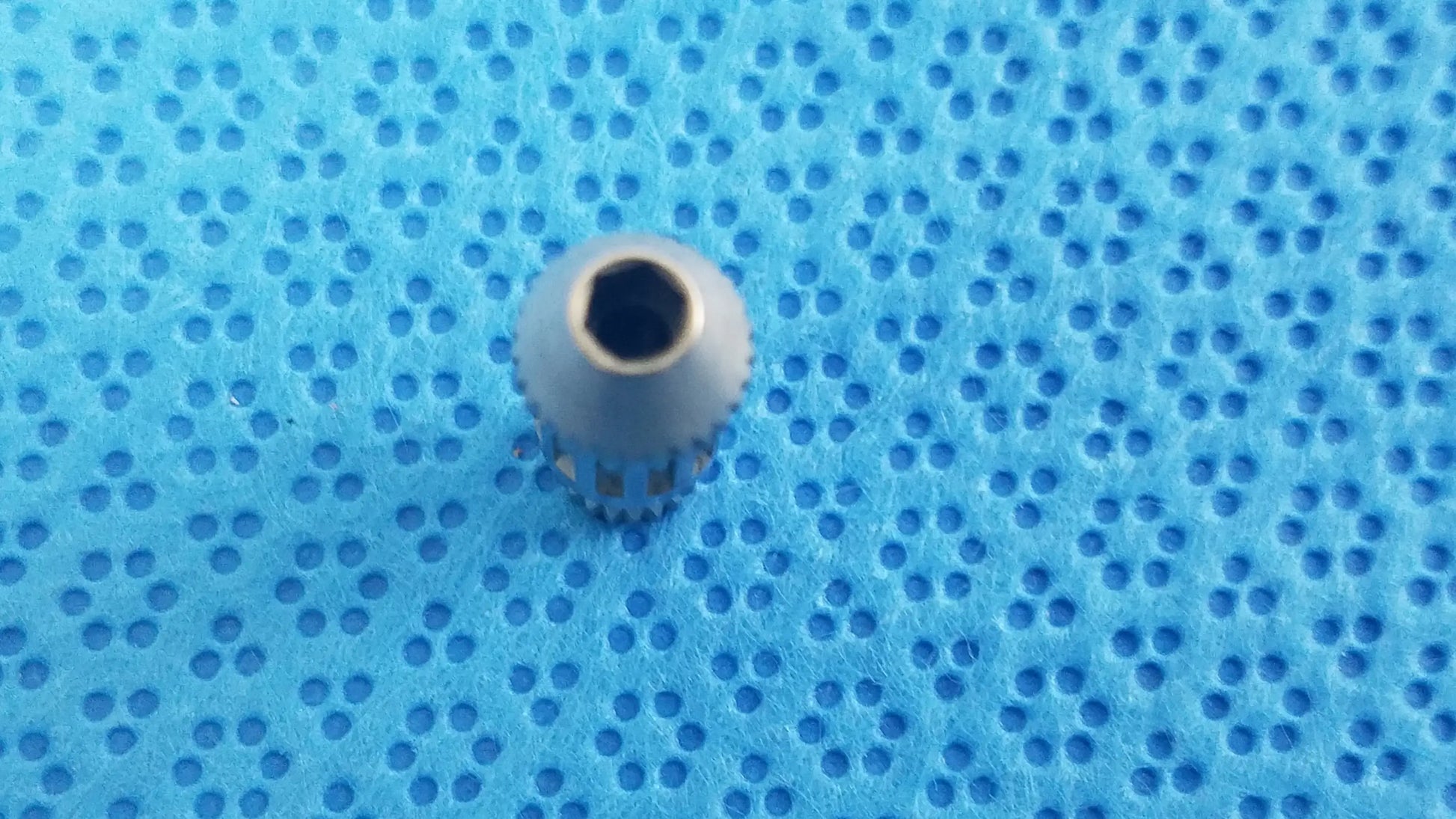 Gray metallic gear with hexagonal center and serrated edge for straumann ultrasonic cleaning cassette in medical equipment reuse