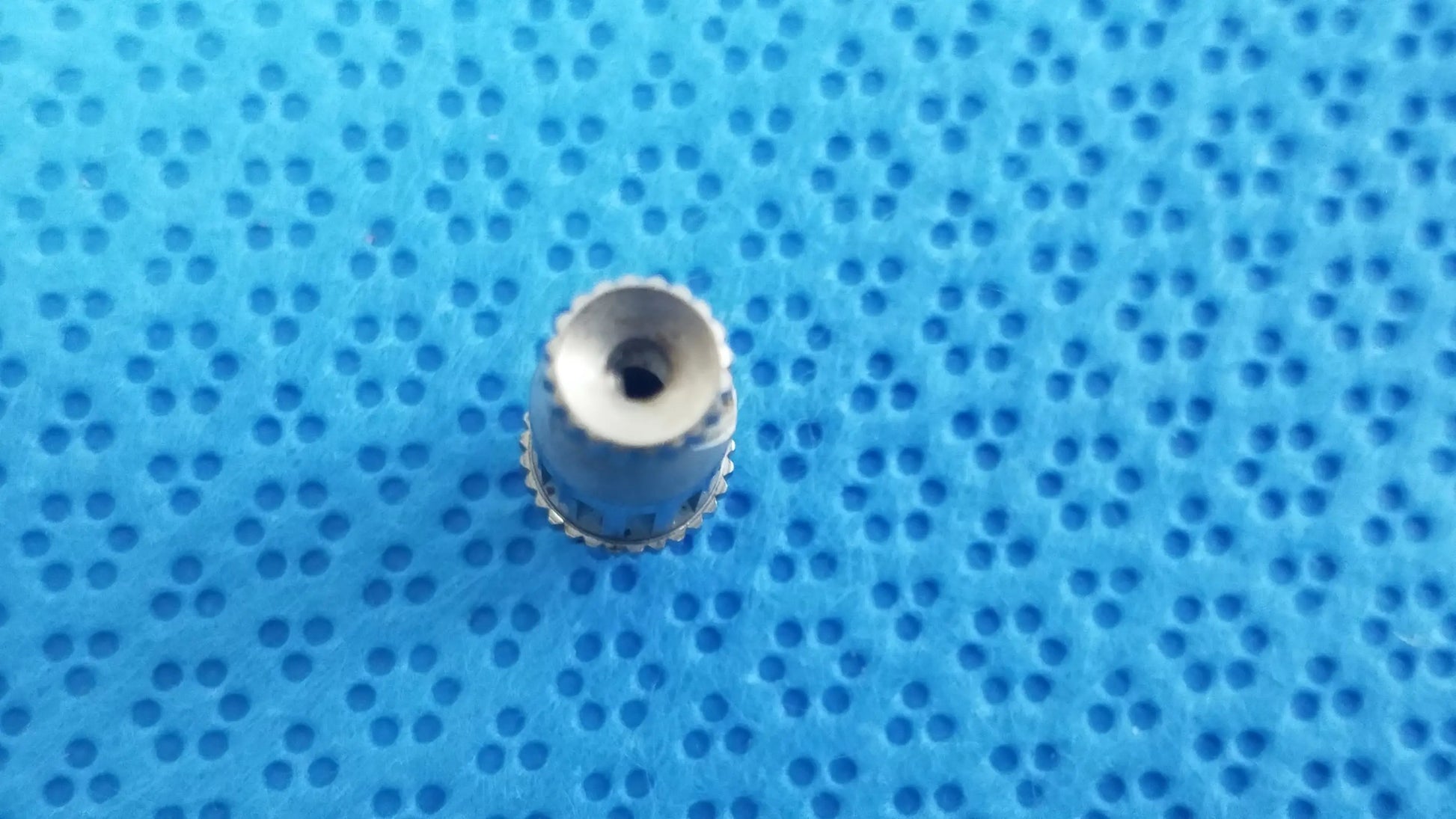 Silver-colored metal watch crown with ridged edge and hole for straumann ultrasonic cleaning cassette reuse medical equipment
