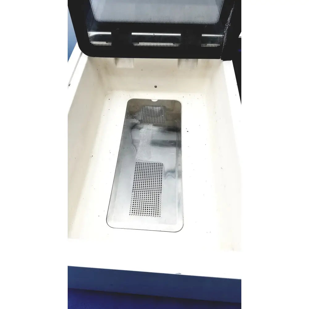 A rectangular perforated metal tray with a reflective surface inside an open white container for straya ref strava splint bath