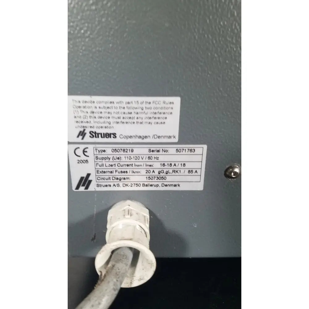 White plastic electrical outlet cover with metallic screw fastener on struers prontopress-20 dual-cylinder metallographic specimen hot mounting machine
