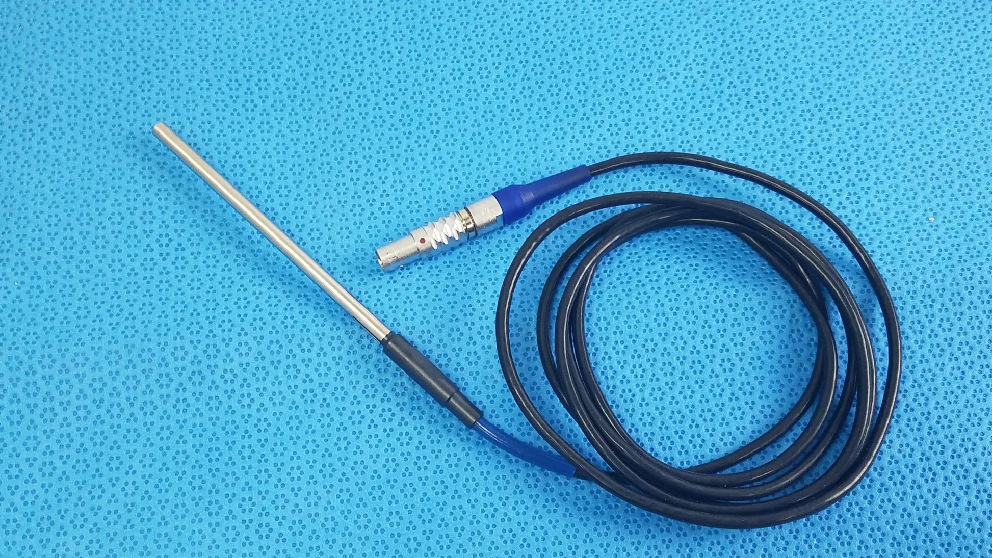 Black coiled cable with blue connector and metallic electrode probe for stryker lightweight sterilization box medical equipment