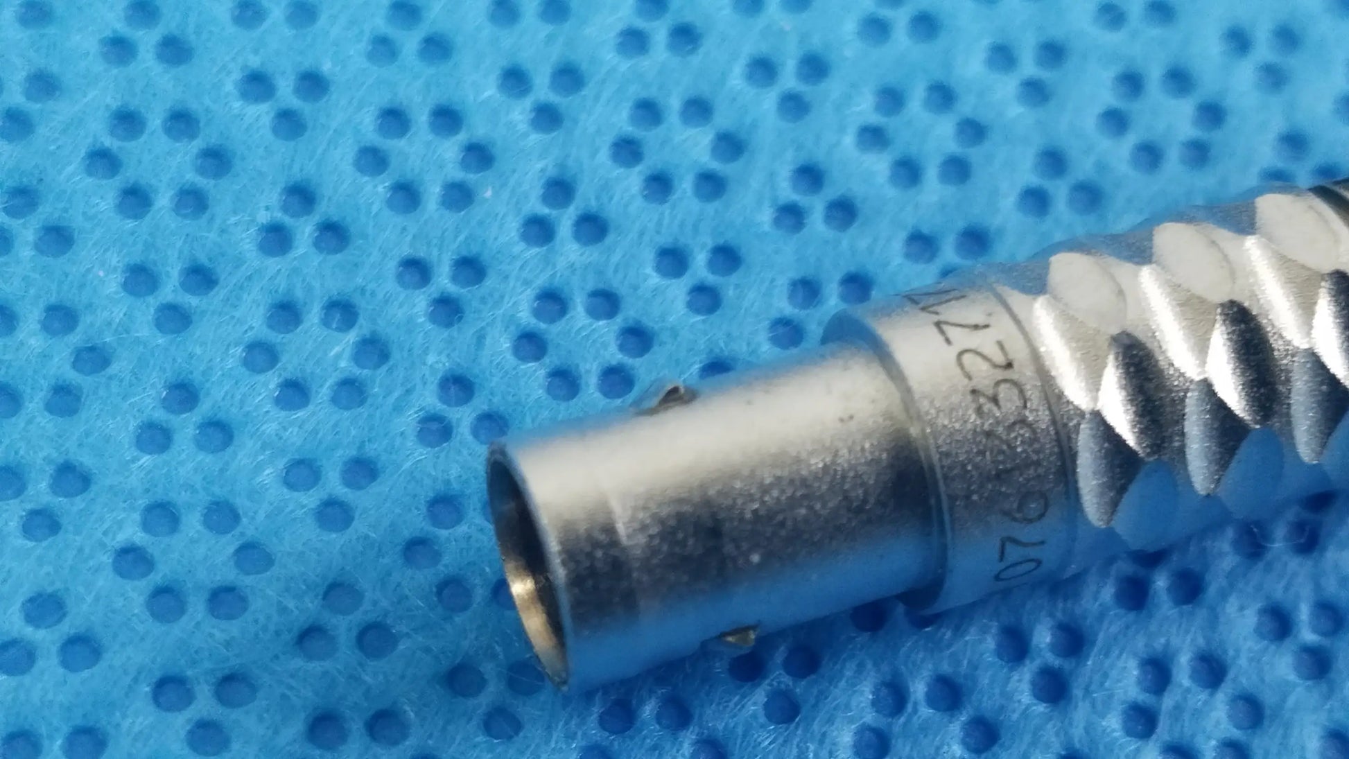 Silver-colored metal bnc connector with threaded exterior and engraved serial number on stryker lightweight sterilization box for medical equipment reuse