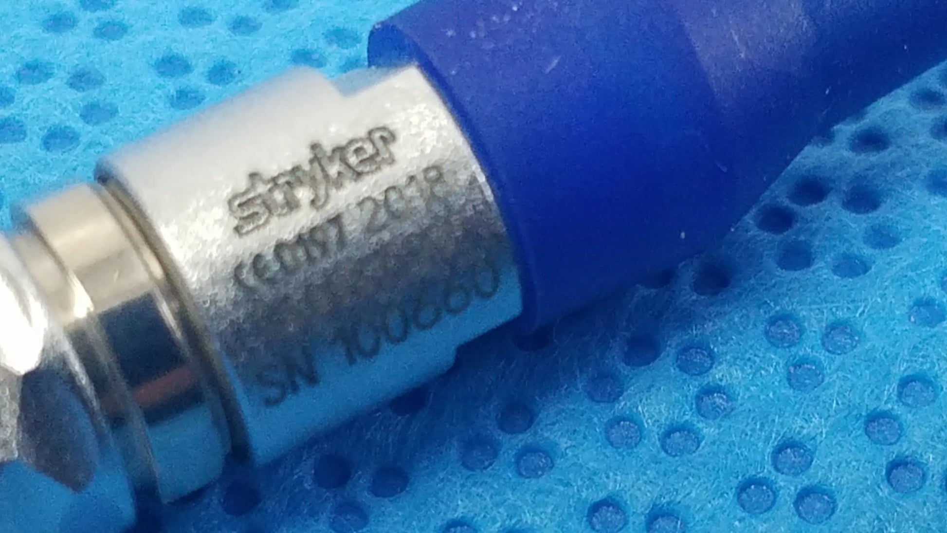 Blue and silver stryker medical connector with engraved serial number for reuse medical equipment in sterilization box
