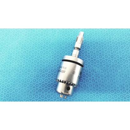 Silver-colored metal keyed chuck with gear-textured surface and engraved markings for reuse medical applications