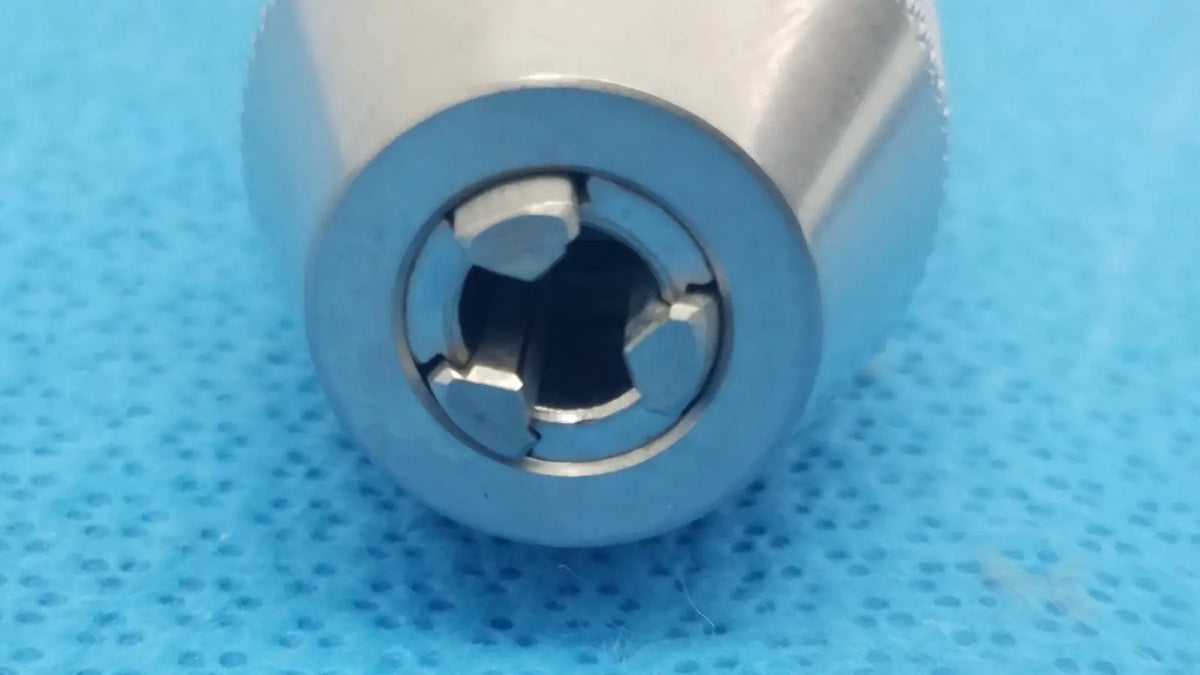 Silver-colored metallic cylindrical keyless drill with cross-shaped internal keyway for reuse medical applications