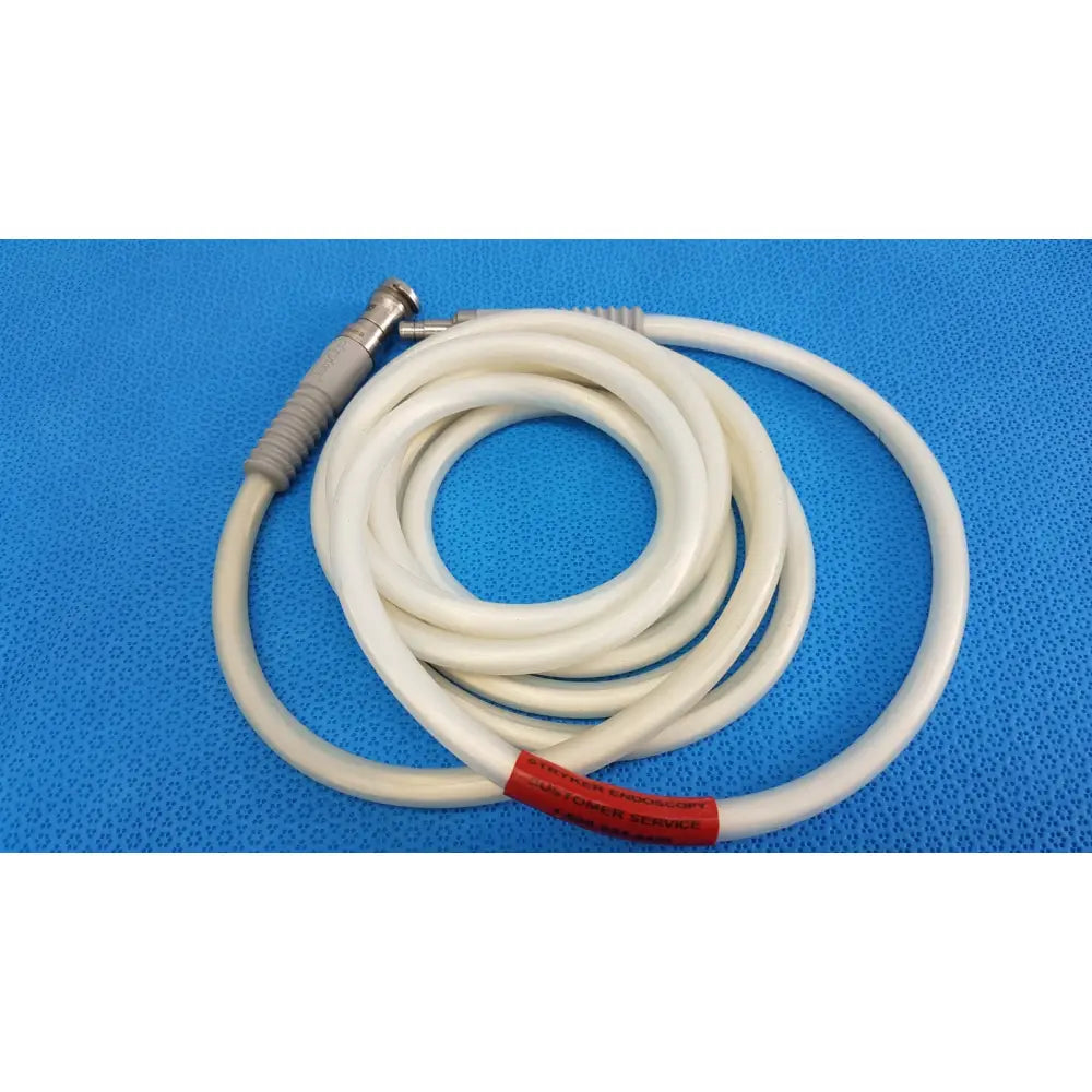 White coiled stryker 195q fiber optic light cable with metallic connector and gray grip for surgical illumination with customer service label