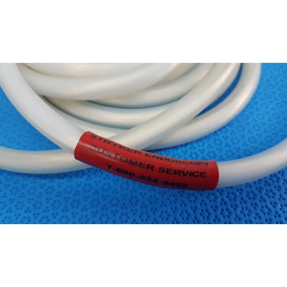 White coiled stryker 195q fiber optic light cable with red customer service label for surgical endoscopic illumination