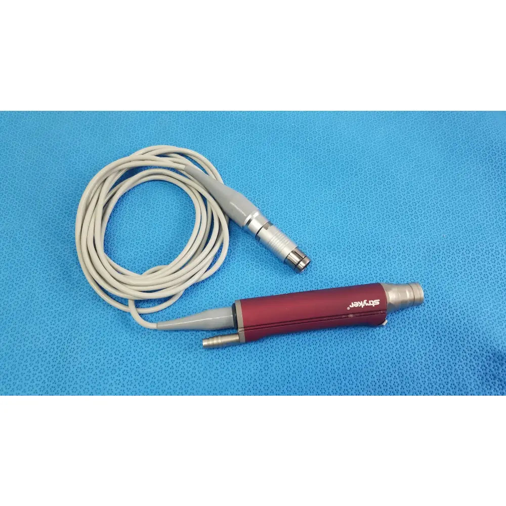 Red and gray Stryker 290-601-100 TPS Leibinger Hummer shaver handpiece with coiled white cable for surgical use