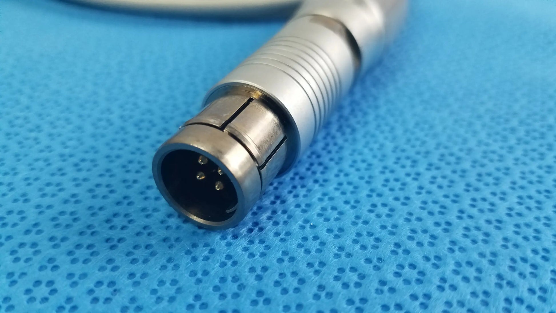 Silver metallic medical-grade connector with cylindrical ridged body and three pins for tps leibinger hummer shaver handpiece