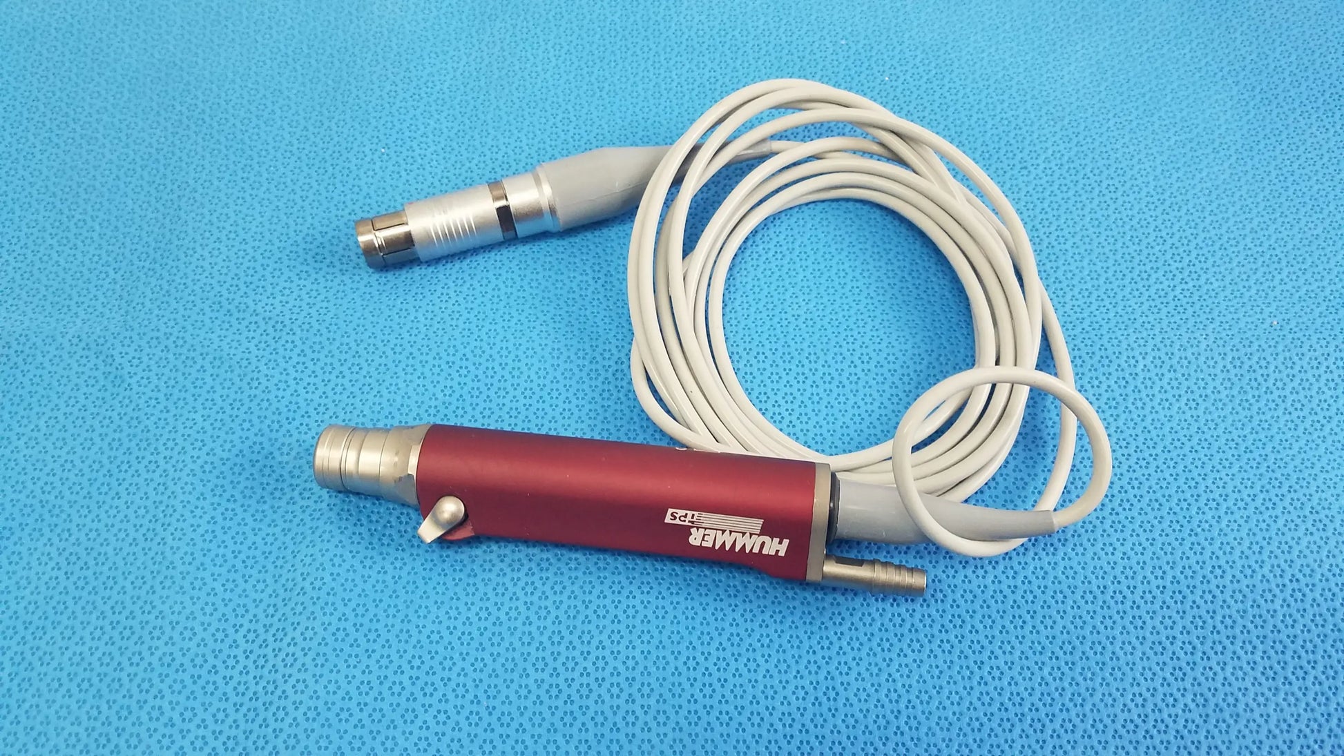 Red and silver tps leibinger hummer shaver handpiece with coiled white cable for precise surgical use