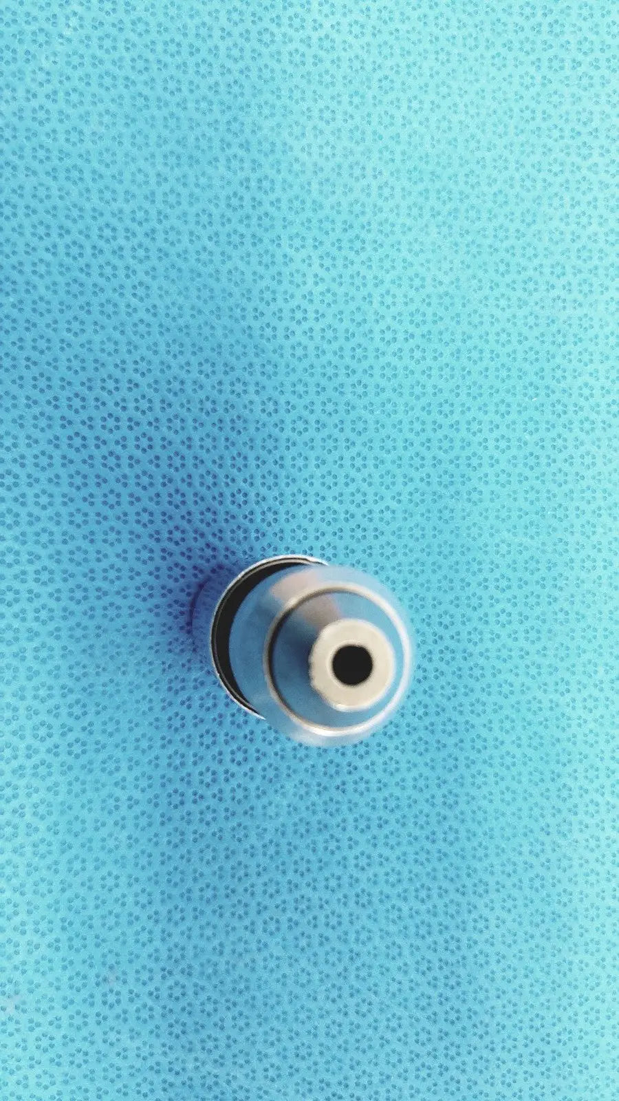Silver metallic synthes style small drill attachment tip with circular hollow center and concentric rings for precise drilling