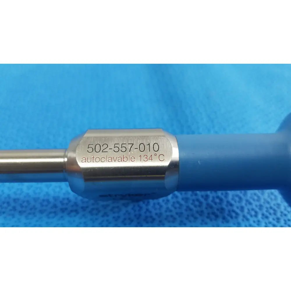Silver metallic surgical ideal eyes 10mm instrument with blue plastic handle and engraved serial number 502-557-010